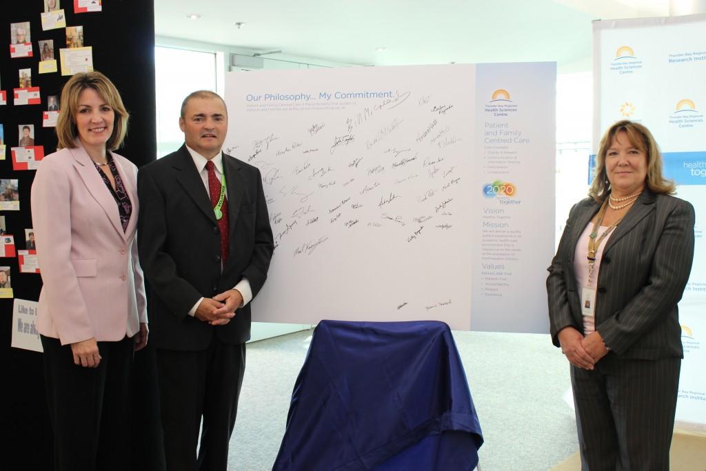Dr. Rhonda Crocker Ellacott, Executive VP, Patient Services and chief Nursing Executive, Keith Taylor, Co-Chair, Patient Family Advisor Council, and Bonnie Nicholas, Patient and Family Centred Care Lead, with the new Philosophy of Care Commitment Boards signed by TBRHSC staff and volunteers. The boards serve as a visual representation of TBRHSC's promise to always put patients and families first.