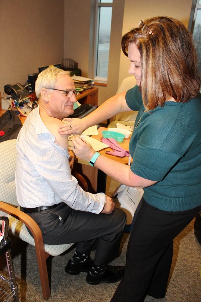 Dr. Bill McCready (Interim President and CEO, Thunder Bay Regional Health Sciences Centre and Interim CEO, Thunder Bay Regional Research Institute) takes the time to get his flu shot from Rose Lazinski, TBRHSC.